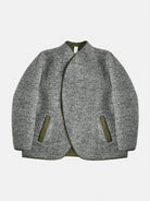 A versatile reversible jacket in grey/dark navy melange, featuring contrasting welt pockets. Its collarless design is shaped with darts for a refined neckline and structured shoulders. The interior mirrors the construction with added patch pockets. Precision piping unites both layers, reinforcing durability and design.

Outer: 80% Wool, 20% Polyester

Reverse: Cotton gabardine (58% Cotton, 38% Polyamide) with a light PU finish in army green

Closure: 8mm gunmetal zipper
