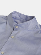 A light blue POCKETPARACHUTE® with Mao Collar by gabrielstunz, featuring white buttons. The shirt is folded neatly with the top three buttons undone, highlighting its sleek, minimalist design and premium fabric texture.