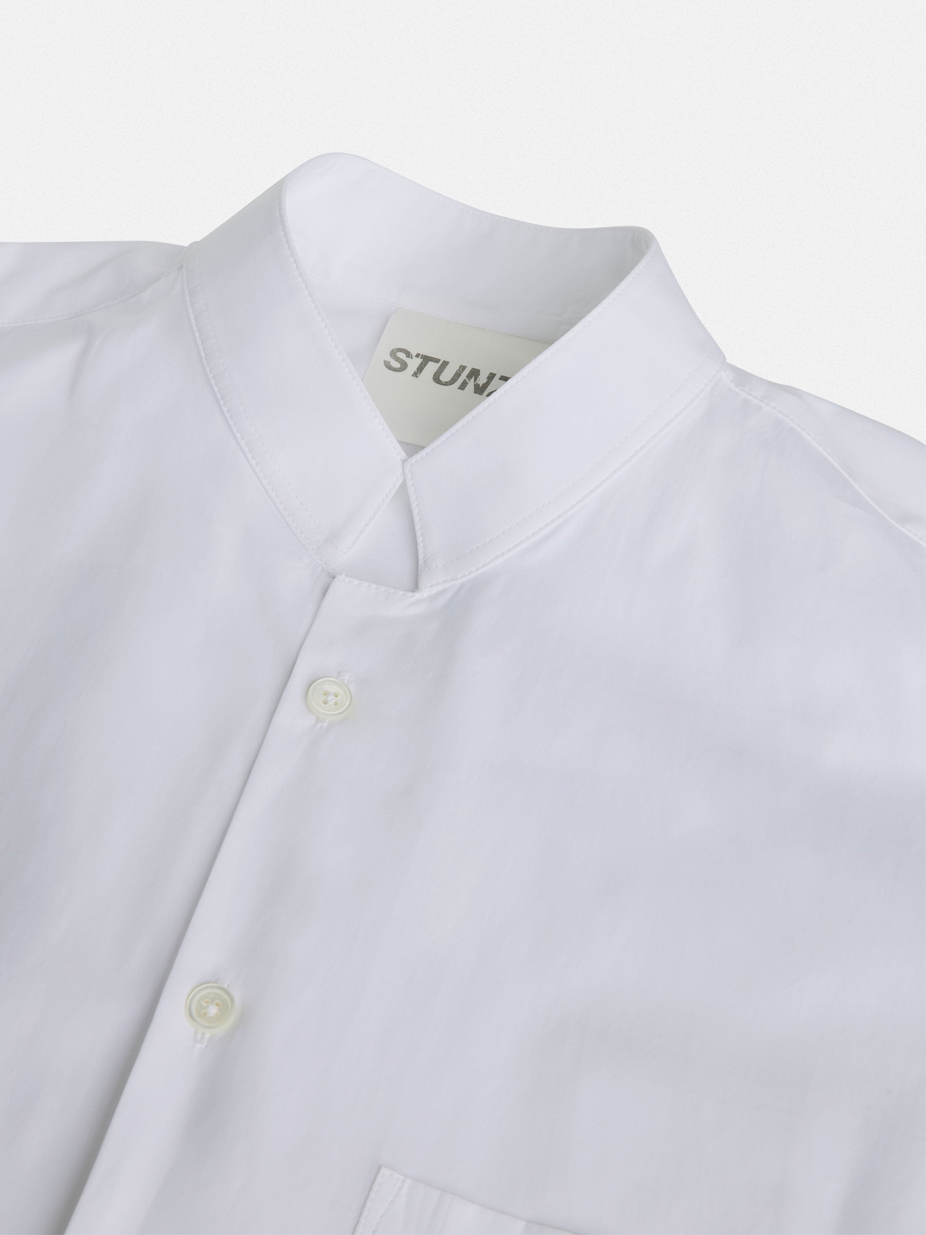 The Mandarin Collar Regular Fit shirt from gabrielstunz is made from 100% cotton by Cottonificio Albini and showcases a front pocket and buttons, displayed on a flat surface. The minimalist design features a label that simply reads STUN.