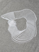 Gabriel Stunz's Oversize T-Shirt features a vortex print with an abstract gray background, highlighted by white concentric lines that form a continuous, irregular loop reminiscent of topographic or ripple effects.