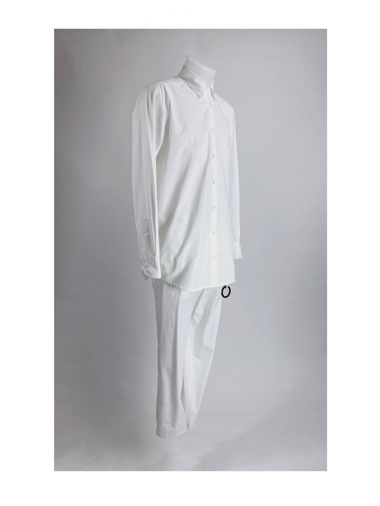 A mannequin is dressed in a monochrome white outfit, consisting of a long-sleeve button-up shirt and matching trousers. The ensemble has a minimalist and formal design, set against a plain white background.