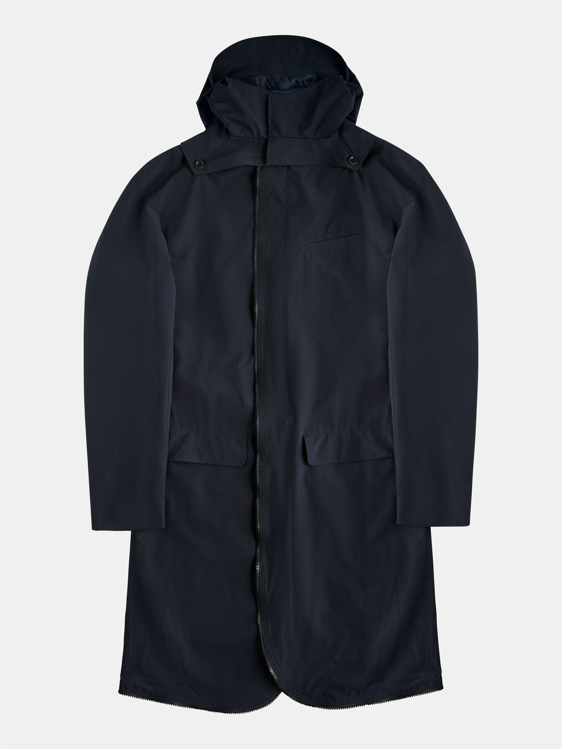 The POCKETPARACHUTE® Tech Raincoat by gabrielstunz in dark navy includes a hood, long sleeves, and front pockets. Made with innovative fabric, it provides the convenience of being packable. Displayed laid flat on a light gray background, the raincoat highlights its full length and front design details.