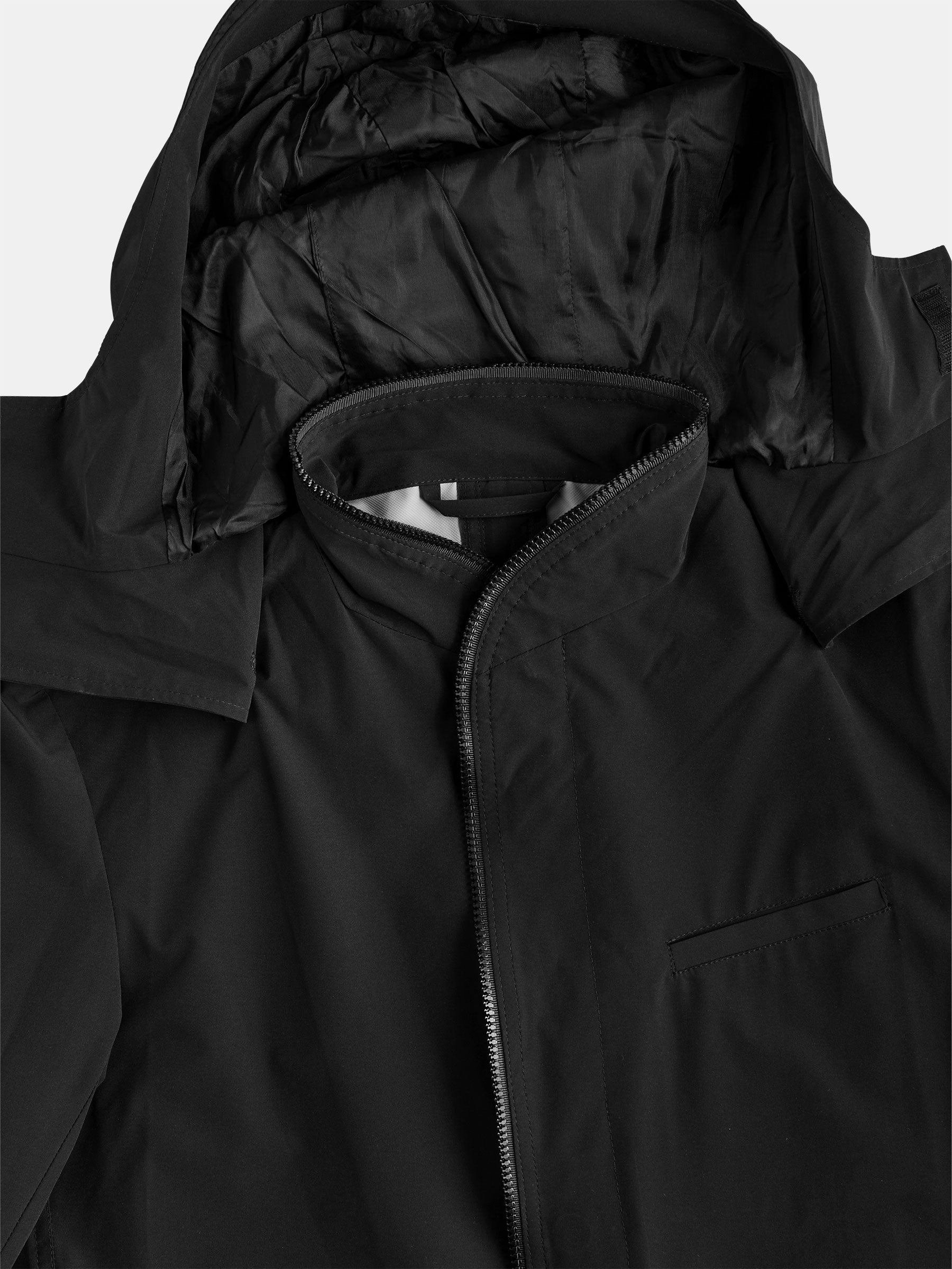 A close-up of the POCKETPARACHUTE® Raincoat by gabrielstunz showcases a sleek black hooded jacket featuring a zipper and a small chest pocket. The smooth, slightly glossy fabric suggests its water-repellent quality. The hood, resting flat, exposes its inner lining, highlighting its practicality as an ideal packable option for unpredictable weather conditions.