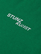 The gabrielstunz STUNZISTKUNST Edition T-Shirt features the bold white text "STUNZ KUNST" printed prominently on a vibrant green background. Crafted from sustainable, organic cotton, this simple yet impactful piece seamlessly combines style with eco-consciousness.